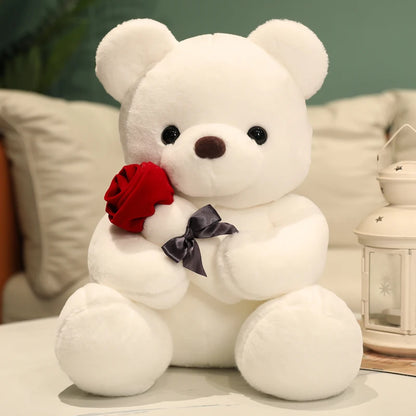White teddy bear holding a red rose on a light surface with a blurred background